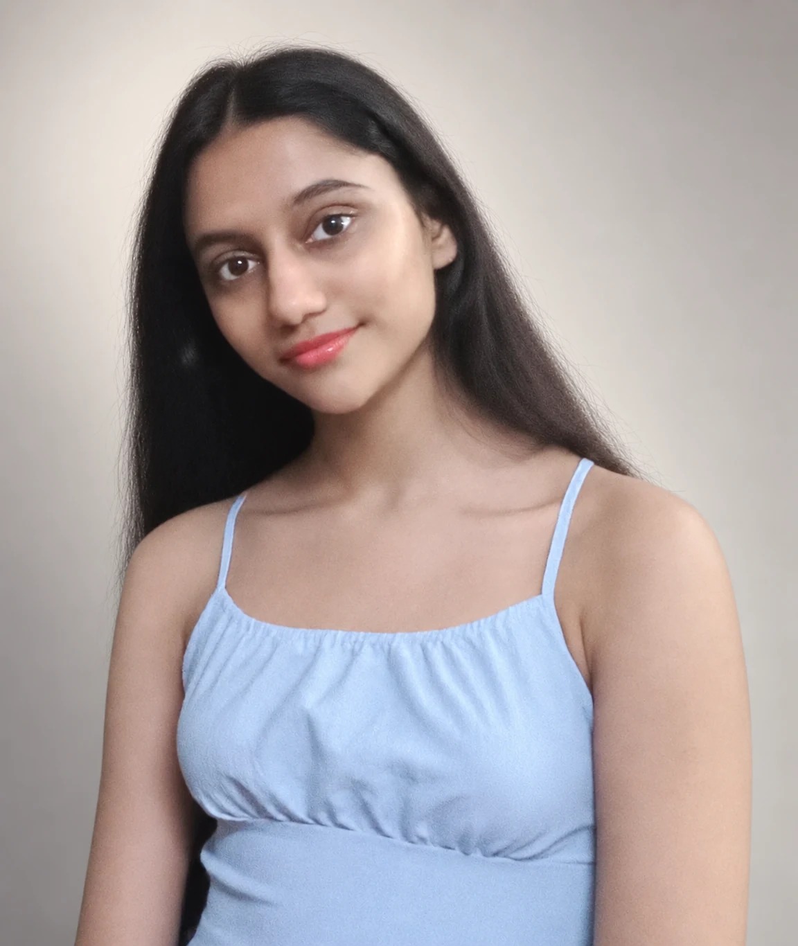 Sreejata in her blue dress against a neutral studio background