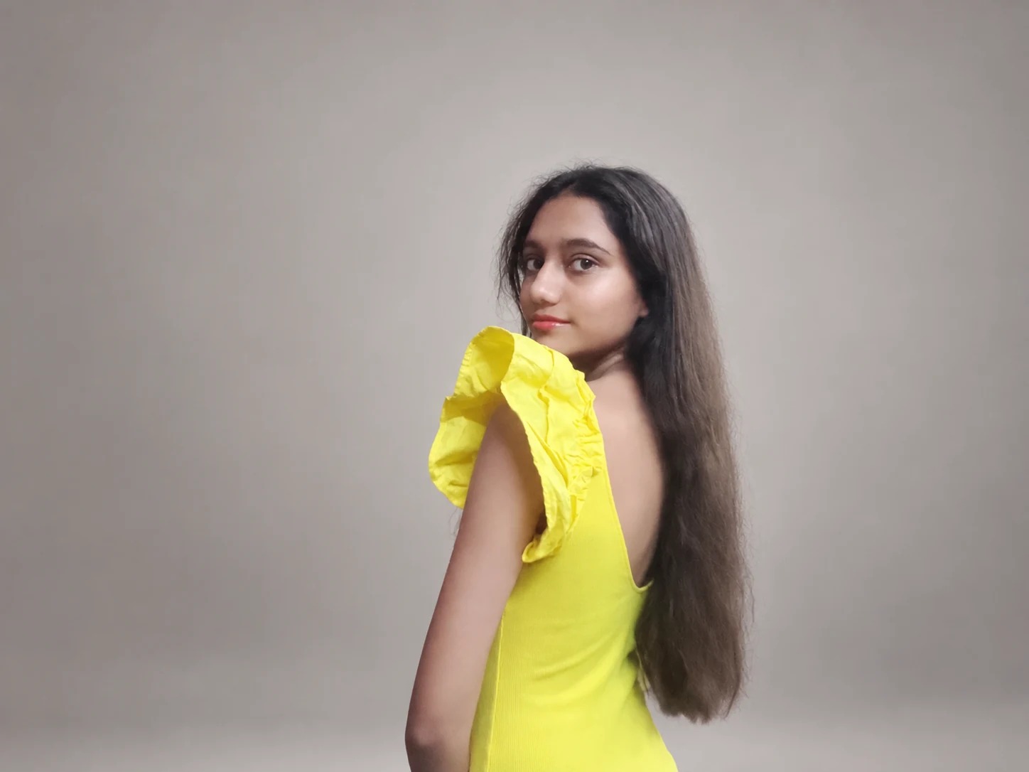 Sreejata looking over her shoulder in her yellow dress
