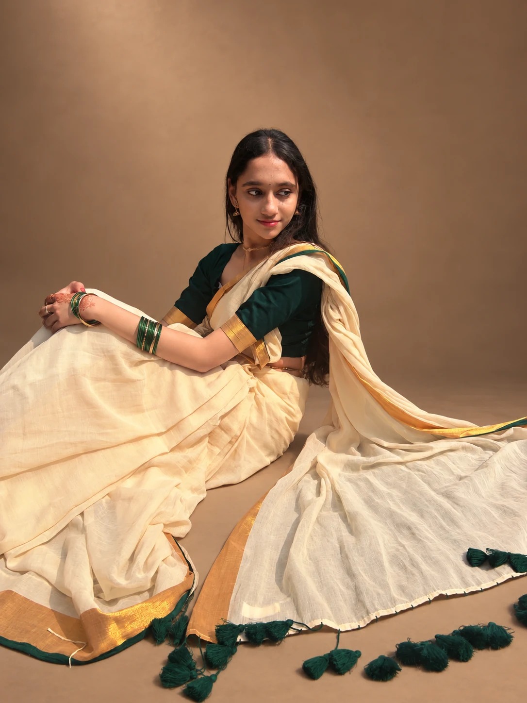 Sreejata seated in her cream sari and green blouse, in a studio setting